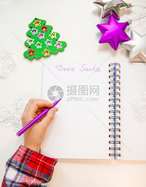 亲爱的圣诞老人信贺卡孩子左手拿着一支笔左撇子在木制背景的白纸上写字新年装饰童梦想的礼物新年概念孩子拿着笔在他的左手一个撇子在木制图片