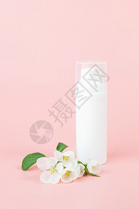 洗剂包裹春天一个白色空化妆品管瓶和花朵粉红色背景上盛开的树枝自然有机Spa化妆品美容概念模型前视图一个白色空化妆品管瓶和花朵粉红图片