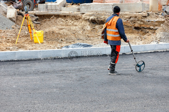 地形一名工程测量路途用一个计量车轮测道路距离确定在公路新段需要倒的沥青量A道路工人用电子计量车对工地进行计量A道路工人用电子计量图片