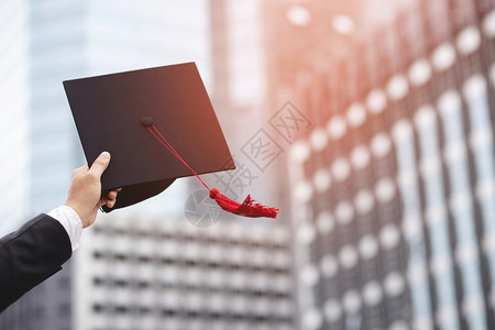 证书背景砂浆板知识未来特写人在背景中展示手持帽学校建筑在大毕业典礼上拍摄帽学位概念庆祝教育学生成功习概念背景
