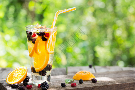 茶点橘子鸡尾柠檬和果浆的在高玻璃杯中的橙子柑橘和浆果中一杯子上挂着根稻草站在木板桌子上浆果之间一片橙子上挂着块树桩喝石匠图片