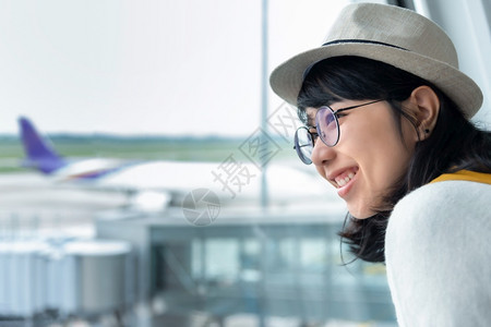 快乐的亚洲年轻女在机场旅途中带着美丽的笑容戴眼镜和帽子享受着愉快的微笑远离情感人目的地积极图片