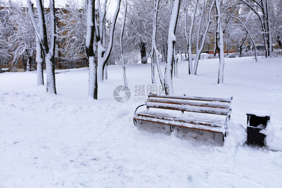 寒冬美丽的户外城市公园小巷的木板凳美景里面盖着雪在复制空间左侧在城市公园小巷铺着雪的Wooden长椅上做广告时图片