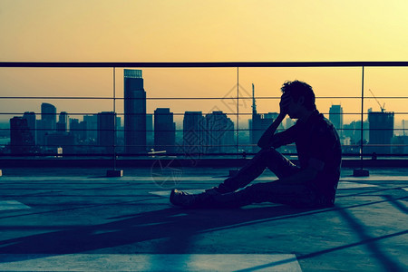 成人日落时坐在Bangkok城市风景的大楼屋顶上人头坐着一个压抑下来的男人看上去像休眠戏剧概念建造单身的图片