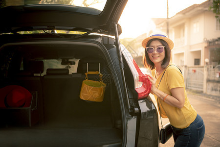 车辆掀背女士旅行时笑着牙齒的女旅行者面对快乐的情绪站在SUV车的背上准备在假期路上出行图片