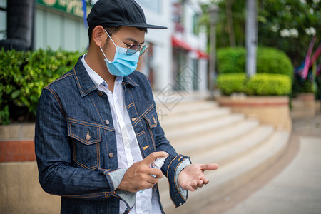 户外使用酒精喷雾洗手的男性图片