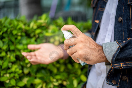 户外使用酒精喷雾洗手的男性特写图片