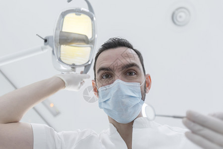戴着口罩给病人做手术的男牙医图片