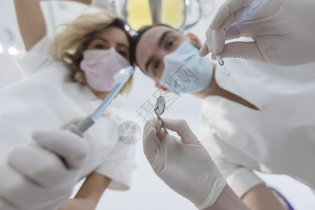 戴着口罩给病人做手术的牙医图片