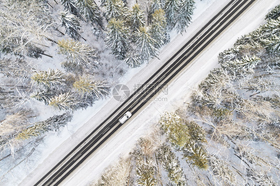 冬季森林中雪覆盖道路的空中景象汽车经过运动模糊景观输风图片