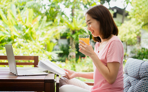 请享用中年亚洲妇女阅读一本书在家中拿橙汁杯健康保概念和为康而吃东西卫生保健城市图片