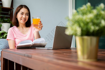 人们快乐的中年亚洲妇女阅读一本书在家中拿橙汁杯健康保概念和为康而吃东西饮食图片