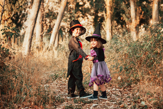 泰迪熊黑色的两个孩子在树林里伪装成万圣节或者图片