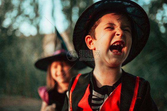 两个孩子在树林里伪装成万圣节孩子们巫婆季图片