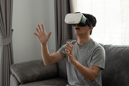 真人喂食游戏玩家一个快乐的男人坐在沙发上戴着3d虚拟真人眼镜情感