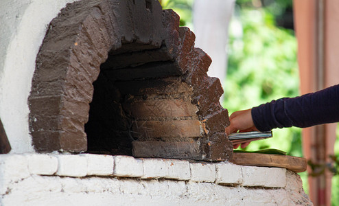制造热的亚洲妇女在家里传统粘土炉烤自家做的比萨饼女士图片