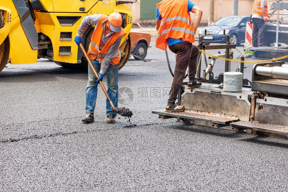 机器建造多层一队道路工人正在沥青摊铺机和压路的帮助下修复一段路在道上铺设一层新的热沥青复制空间一队道路工人正在用业道路机械铺设新图片