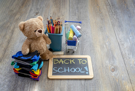 配件回到学校概念的TopSeaTeddy熊站在木地板上旁边有一堆儿童袜子纸板彩铅笔和购物纸桌中的彩粉笔黑板课堂图片