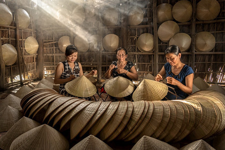 福抽烟棍子越南霍希明市ApThoiPhuoc村老旧传统房屋中越南女工匠集团传统艺术家概念传统艺术帽外衣的越南女工匠集团图片
