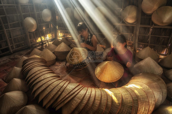 旅行精神在越南霍希明市ApThoiPhuoc村古老的传统房屋中两名越南姐妹手工艺师在传统术家概念中制作传统维特南帽热带图片