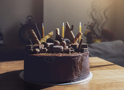 Home做了巧克力蛋糕背景模糊的起居室背景巧克力软糖蛋糕和黄色金质装饰品生日蛋糕创意等巧克力面包棕色的活吃图片