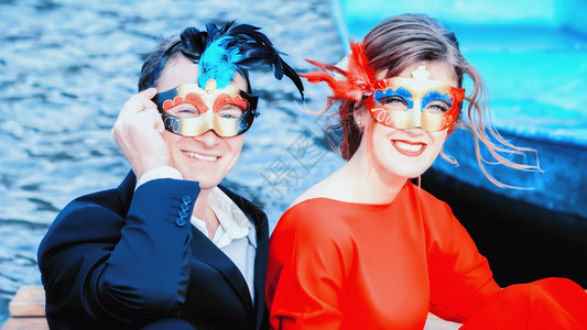 美丽的一对穿着化妆面具的快乐年轻夫妇红蓝肖像穿着优雅装饰的男女在湖边笑着关注前方欢乐的人与女在化妆面具中品蓝色的图片