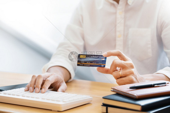 支付信用卡和进入安全码的男子在互联网上用笔记本电脑在线购物概念付款或买货物的网上商店交易时使用信卡和进入安全代码的人银行室内卡片图片