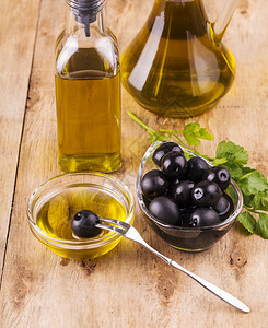 乡村液体烹饪维尔京橄榄油和健康的油瓶子和杯旧木制餐桌面上与食的欧利酒杯图片