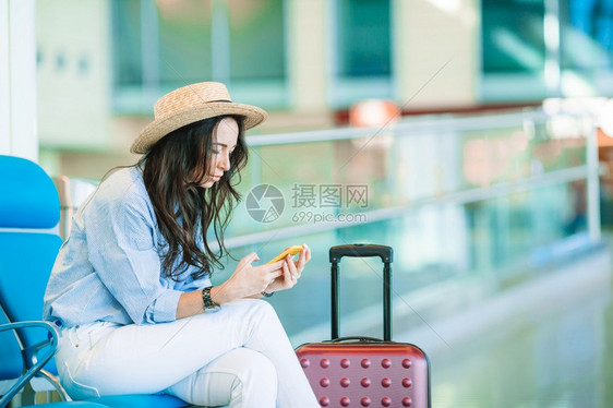 运输手提箱戴帽子在国际机场携带行李的年轻女士等待乘坐飞机的年轻女士在国际机场携带行李的年轻女青士登机图片