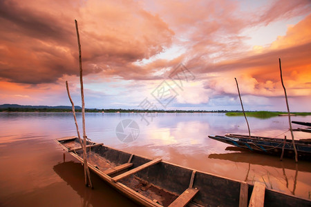 湄公河上空的戏剧日落天空前方浅滩上的老木式渔船黄昏云景晚上背景图片