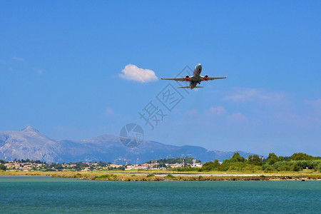 在希腊科孚机场开起一架飞海上短而危险的空机山丘背景的海面上是高山旅行地标中海图片
