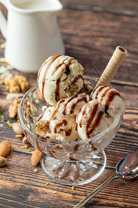 黑暗的食物杏仁冰淇淋和核桃花兰冰淇淋在玻璃碗里加焦糖酱甜的图片