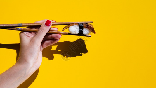 寿司促销代金券高清晰度照片持有寿司筷子的妇女黄色背景高质量照片优雅的摄影师复制三文鱼促销背景