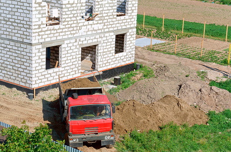 俄罗斯一种辆卡车和栋用白砖制成的建筑物垃圾车将沙子带到建筑工地这是在建房屋附近的一辆倾卸卡车地点图片