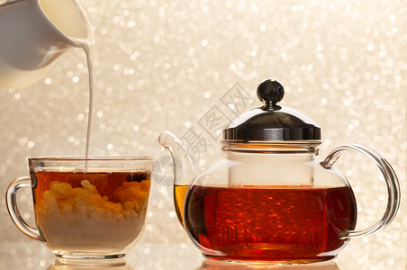 美味的分支黑色在一杯茶中溶解牛奶透明茶壶和杯子清洁茶壶和杯子黑透明壶和子背景模糊的图片