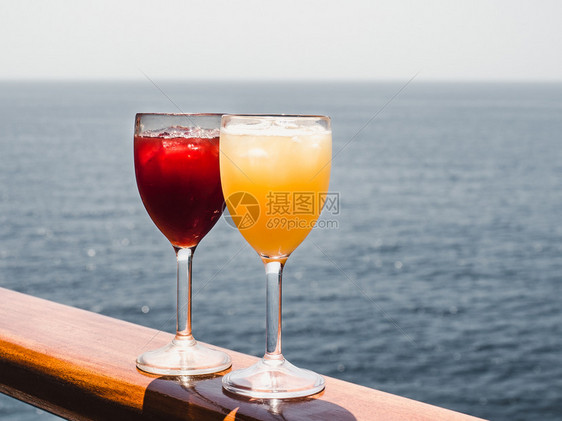 日落红酒杯喝美丽的有鸡尾和冰块在海浪的背景下站在露天的甲板上侧观休闲和旅行的特写概念玻璃与鸡尾酒和冰块图片