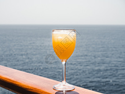 一种海洋美丽的酒杯有鸡尾和冰块在海浪的背景下站在露天的甲板上侧观休闲和旅行的特写概念玻璃与鸡尾酒和冰块日出图片