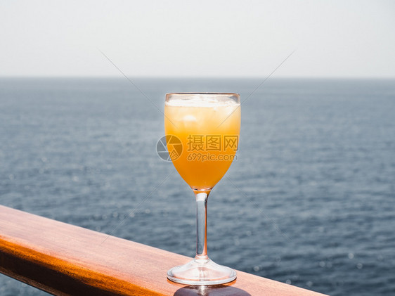 一种海洋美丽的酒杯有鸡尾和冰块在海浪的背景下站在露天的甲板上侧观休闲和旅行的特写概念玻璃与鸡尾酒和冰块日出图片