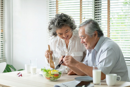 快乐的亚洲老年夫妇在家里放松准备和烹饪健康沙拉与浪漫的老年男女一起微笑着享受顿饭的笑容亚洲人桌子乐趣图片