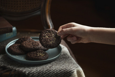 巧克力饼干在盘子上黑暗和穆迪神秘的轻食物摄影儿童手从盘子上拿一块饼干糖吃优质的图片