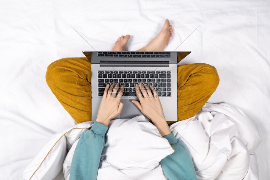 互联网女孩手在家里的床上使用现代笔记本电脑的顶视图家庭办公室或在线教育概念笔记本电脑放在女膝上手在家里的床上使用现代笔记本电脑的图片