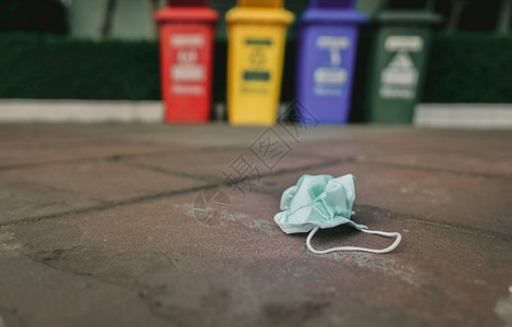 个人的用医疗面罩丢弃在模糊的回收垃圾桶或铺在路面地板上用不卫生可溶耳环处理的医疗废物与地板绿色外科手术面罩一起处置颜色图片
