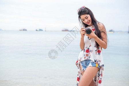 松弛快乐的数字亚洲女人喜欢在海滩上用数码相机拍照单身和孤独的女人概念幸福和生活方式概念美丽和自然主题海洋背景技术女人节图片