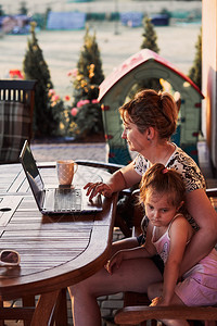 商业真实的母亲在家工作使用便携式计算机在夏季日与女儿一起坐在院子上Candid人真实时刻情况等妈图片