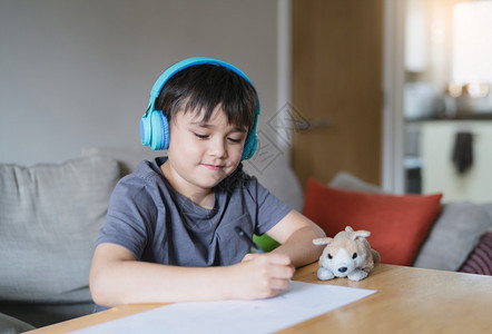 可爱的穿着耳机快乐孩子在画纸时聆听音乐室内肖像Cute男孩享受周末在家的创造活动爱好年轻的图片