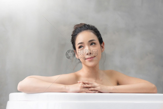 微笑的美丽亚洲女孩在浴缸里放松家肖像快乐年轻迷人的女在浴室洗间澡时在浴缸里放轻松亚洲人奢华吸引的图片