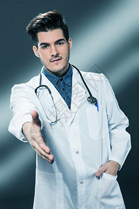 友善的微笑医生伸出手来与灰色背景握手军医快乐的专业图片