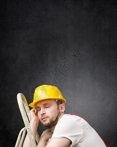 承包商疲劳的懒建筑工人睡在梯子上一个带懒惰工人的肖像复制图片