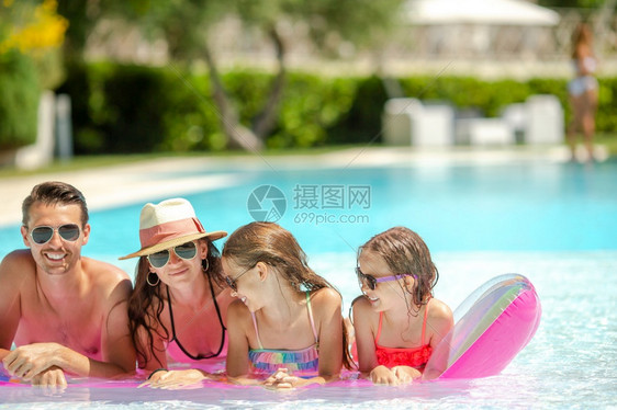闲暇有两个孩子的年轻家庭在户外游泳池享受暑假有两名孩子的年轻家庭在户外游泳池享受暑假太阳镜热带图片