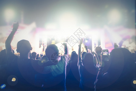 人类音乐会群众在节日观看后举手向明亮的舞台灯升起岩石居住图片